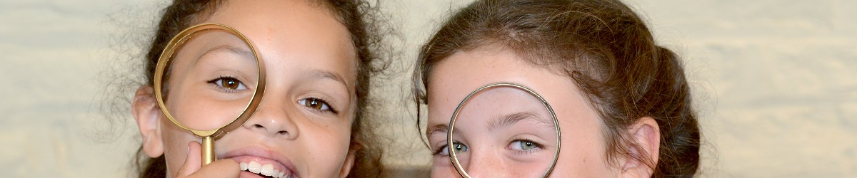 Two young girls smile as they spy with magnifying glasses they've made at a craft activity